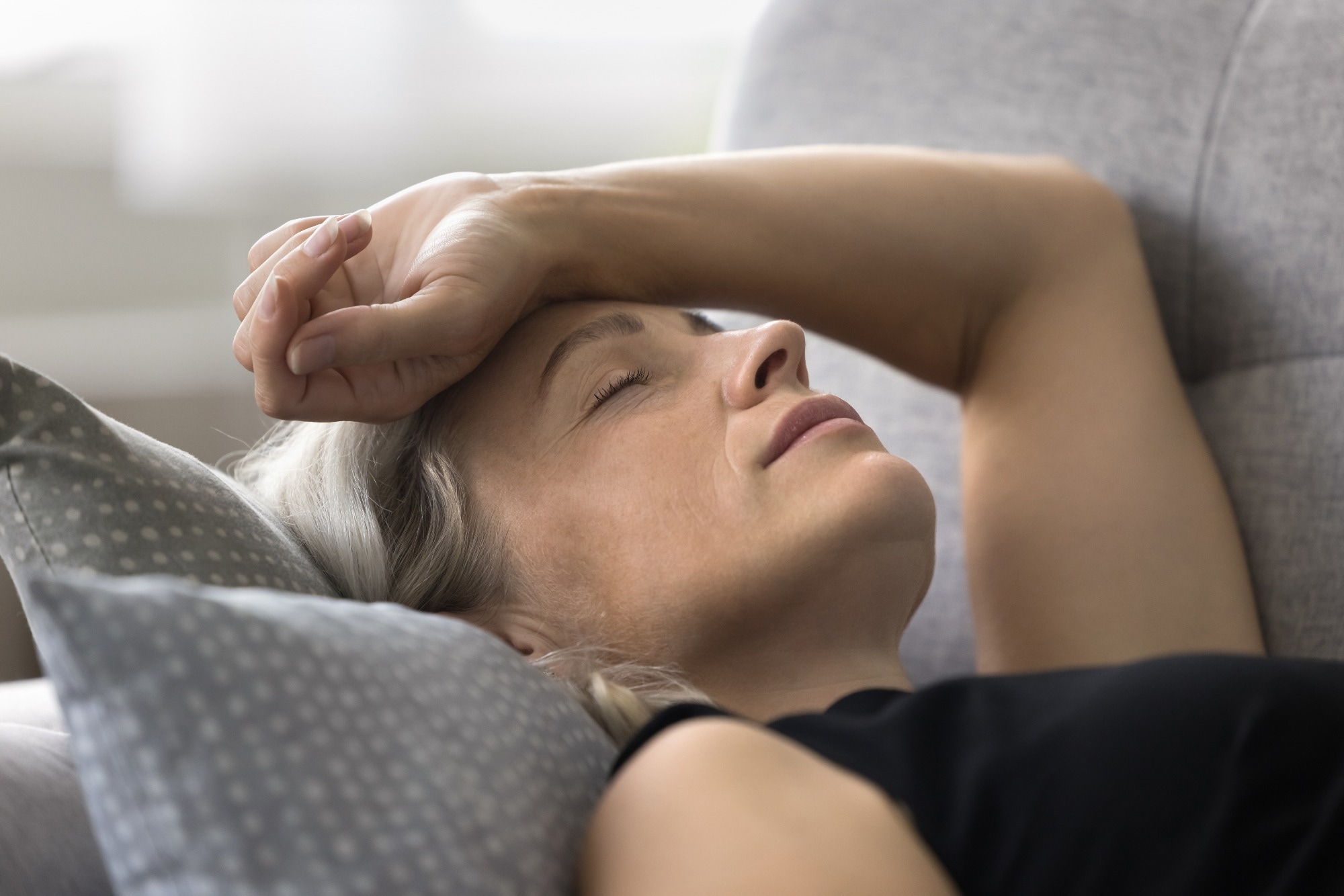 Weak senior woman lie on sofa.