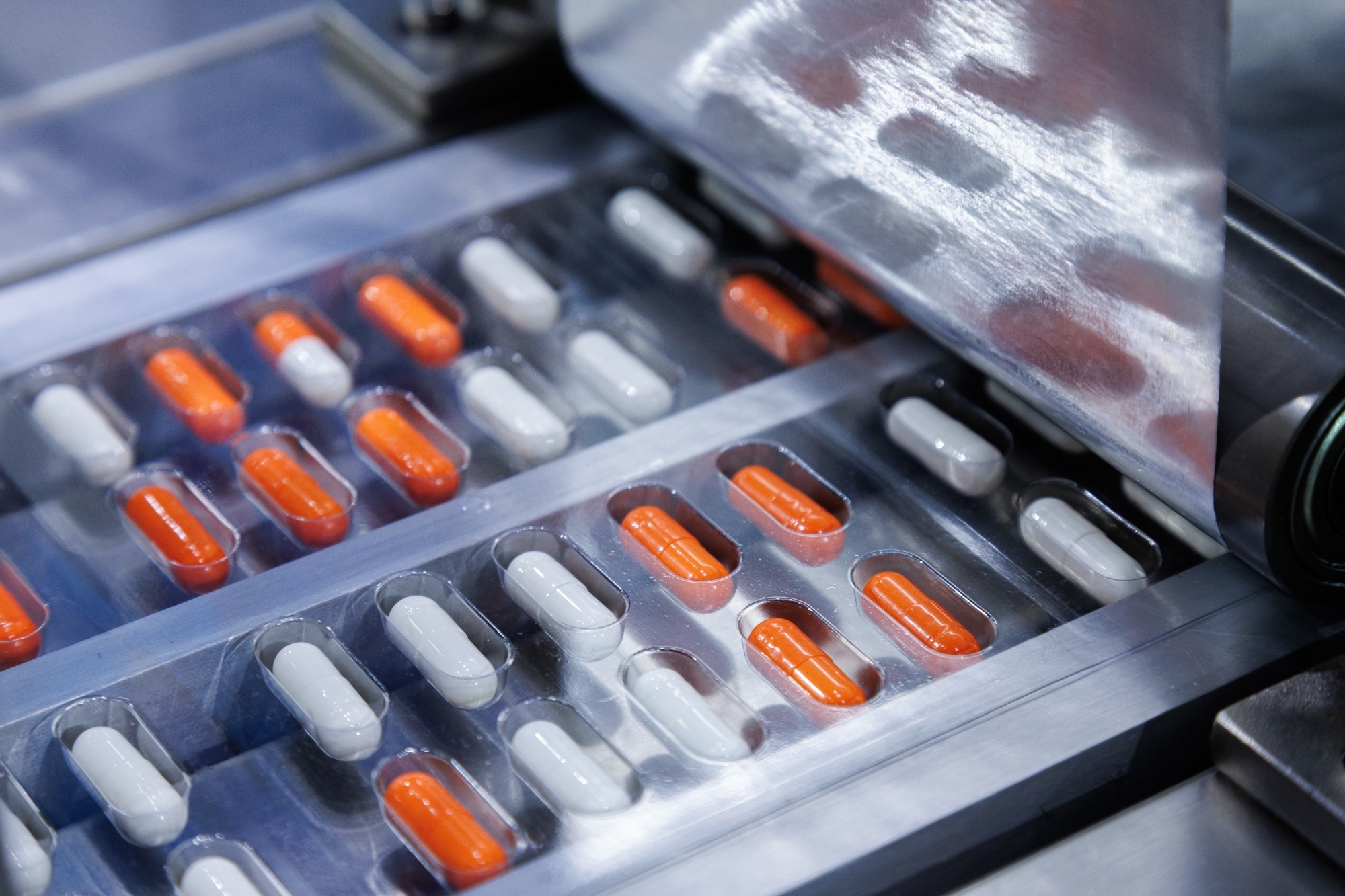 automated medicine packaging machine for orange and white capsules.