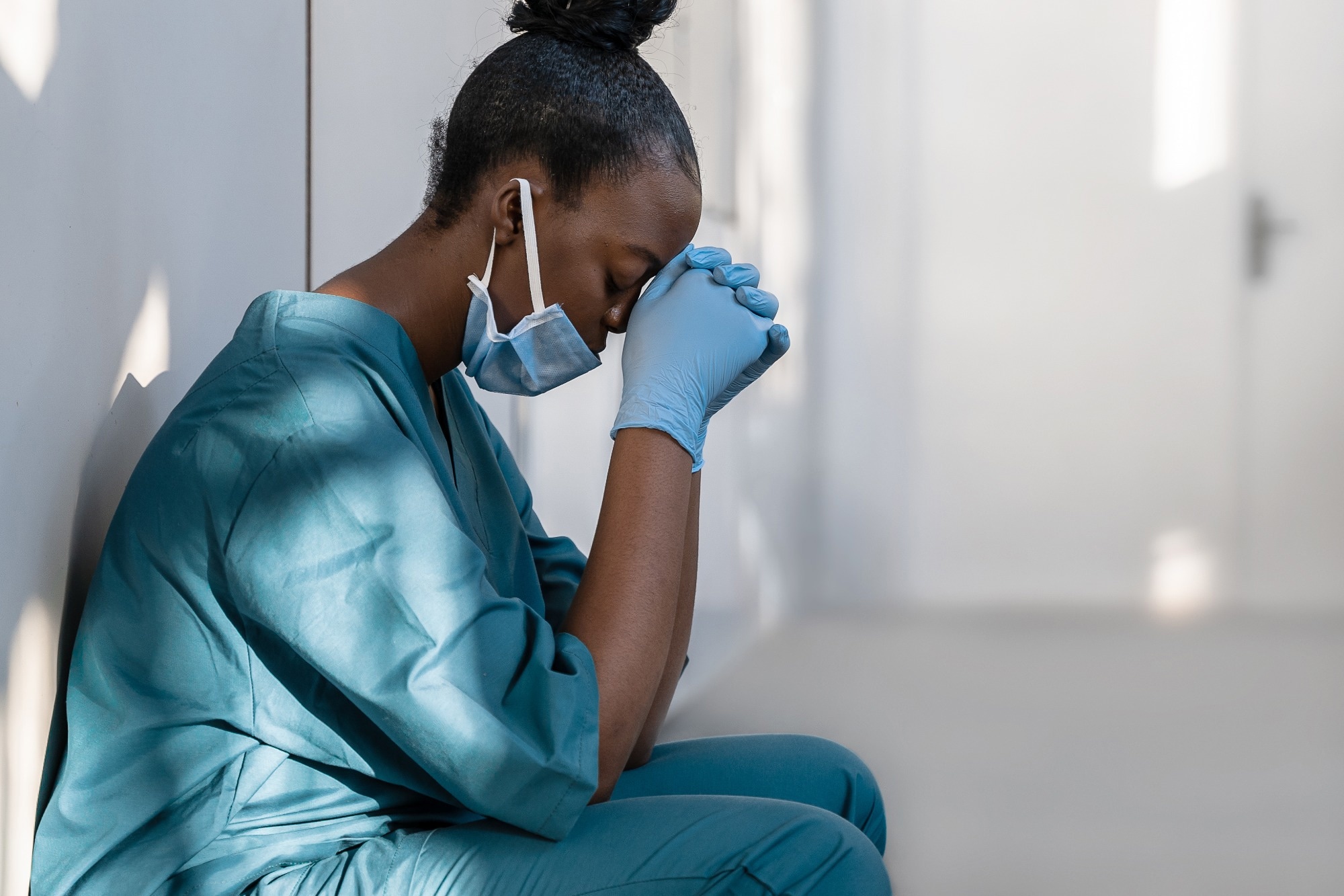 Masked health care worker with head in hands