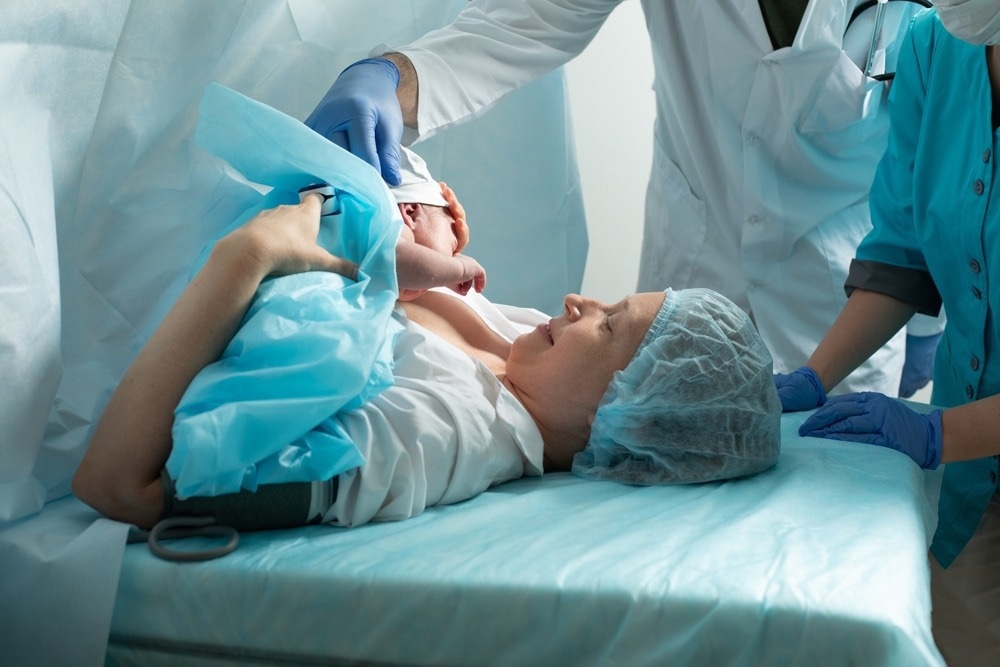 Mother looks to her newborn baby in hospital after a cesarean
