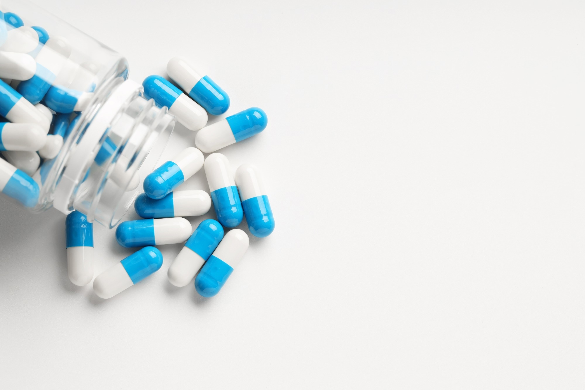 Antibiotic pills and bottle on white background, top view.