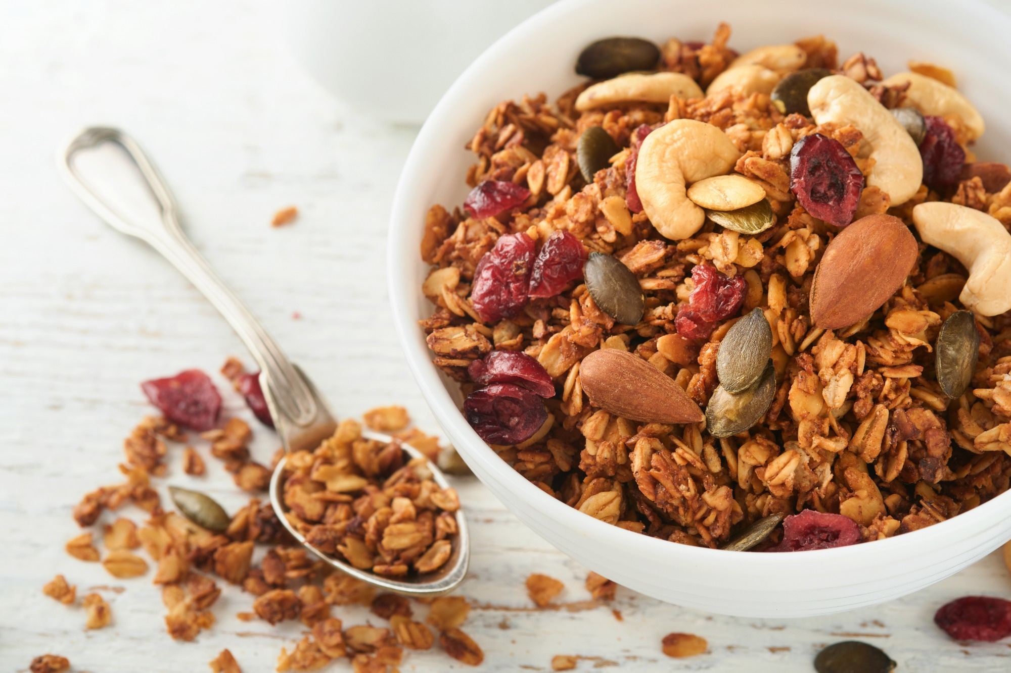 Homemade granola in glass jar with greek yogurt or milk and cashews, almonds, pumpkin with dried cranberry seeds
